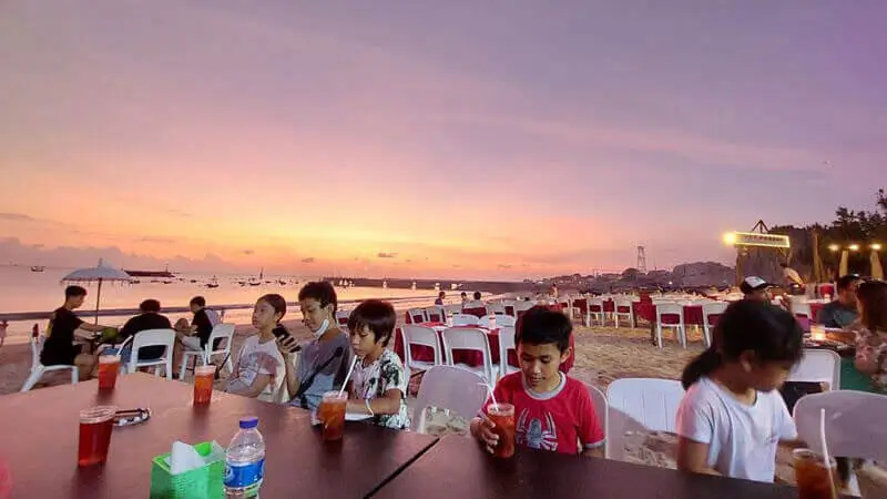 Suasana makan malam di Pantai Jimbaran dengan latar sunset yang menawan