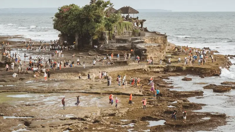 Wisatawan menikmati suasana di sekitar Pura Tanah Lot Bali saat air surut