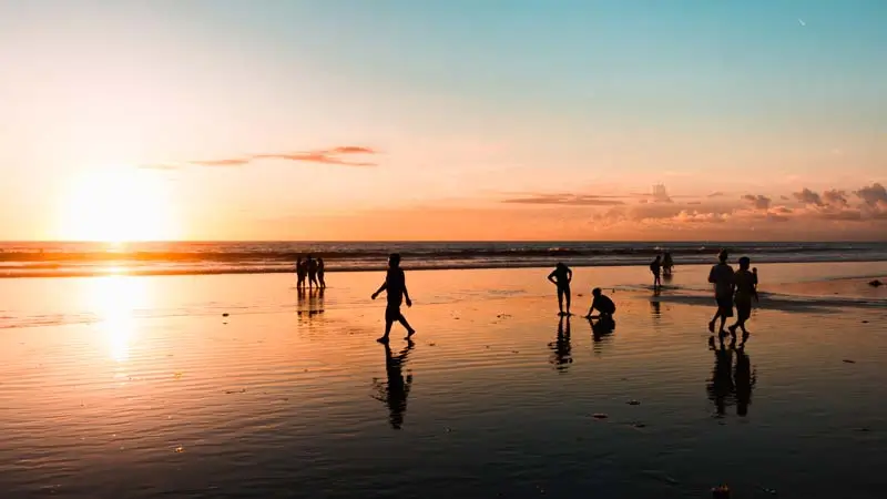 Siluet wisatawan menikmati senja di Pantai Kuta